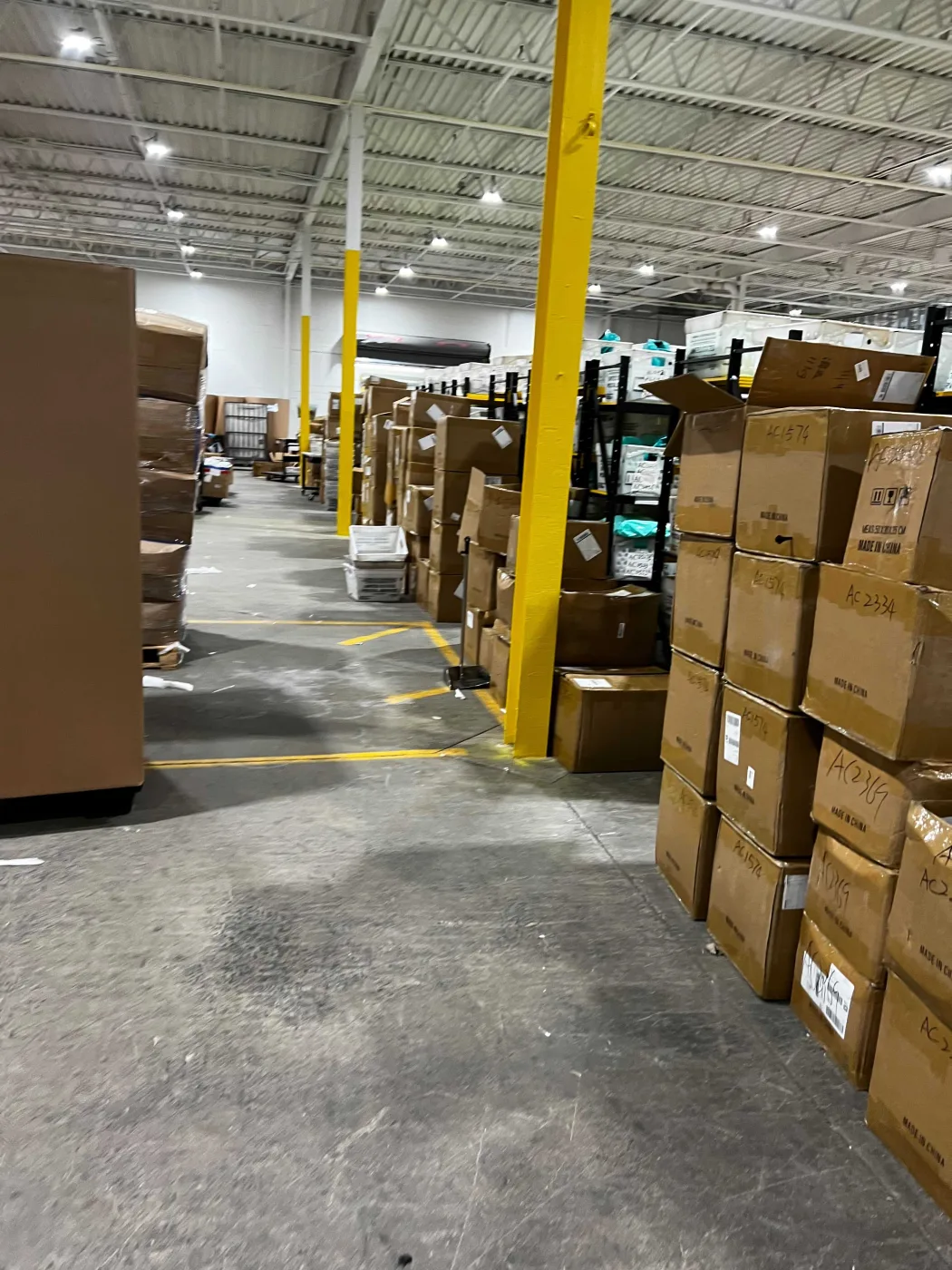 Wide aisle lined with stacked cartons on pallets