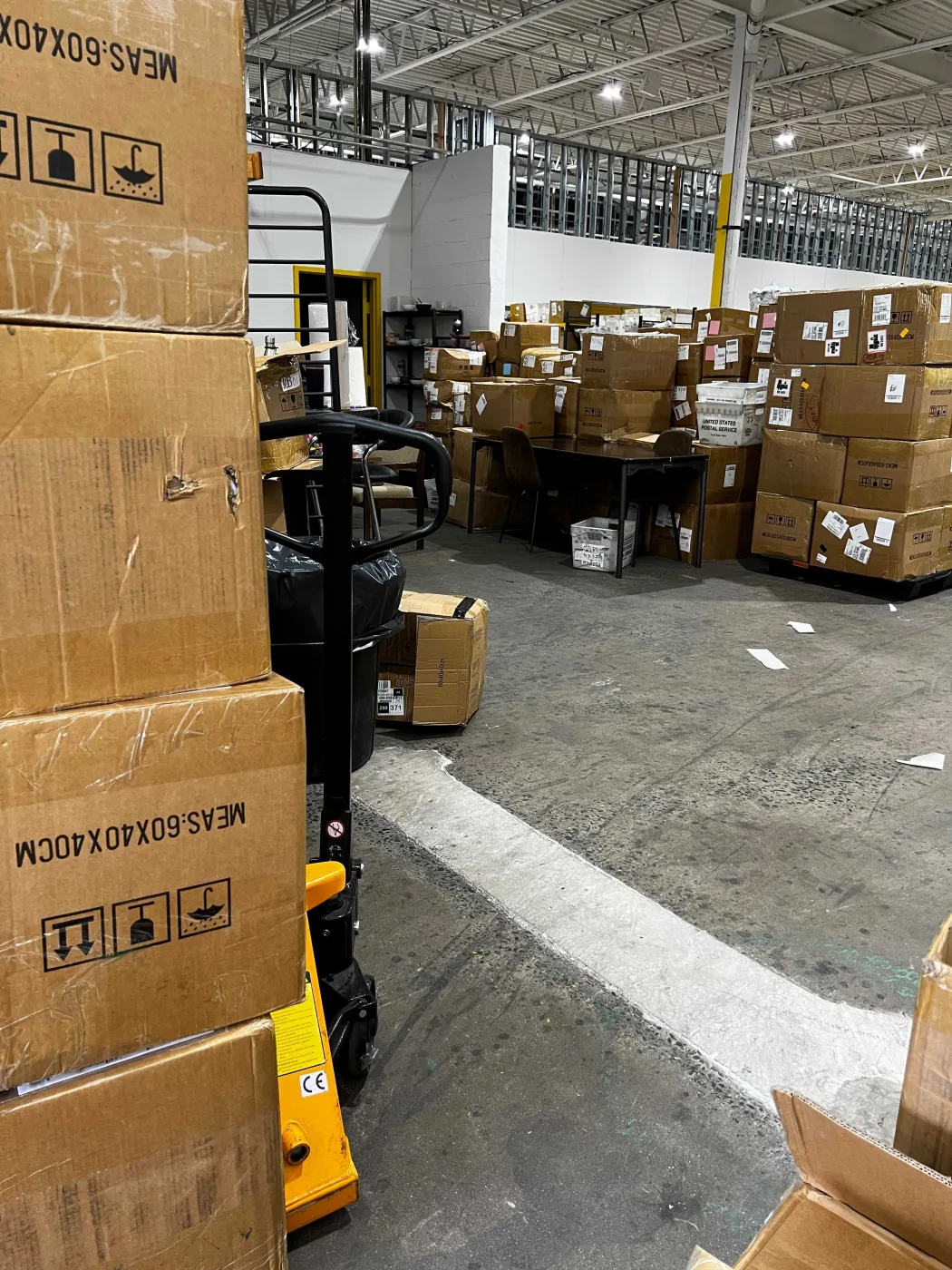 Pallet jack beside stacked cartons on the warehouse floor